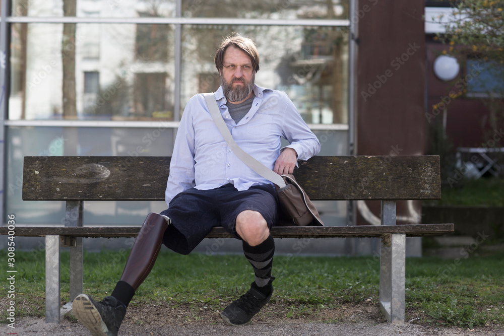 older man with prosthetic leg sitting on a bench older man with prosthetic leg sitting on a bench