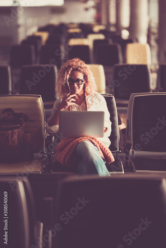 Caucasian people beautiful middle age young woman sit down on a wait seats at the airport or station using personal modern laptop computer to work - digital nomad concept lifestyle and travel lady