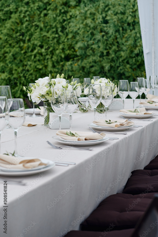 Table setting with sparkling wineglasses and cutlery in tent outdoors, copy space. Place setting at wedding reception. Table served for wedding banquet in restaurant Table setting with sparkling wineglasses and cutlery in tent outdoors, copy space. Place setting at wedding reception. Table served for wedding banquet in restaurant