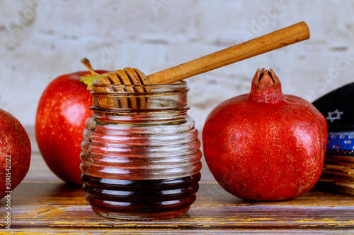 Pouring honey on apple and pomegranate with honey symbols of Jewish New Year - Rosh Hashanah. photo