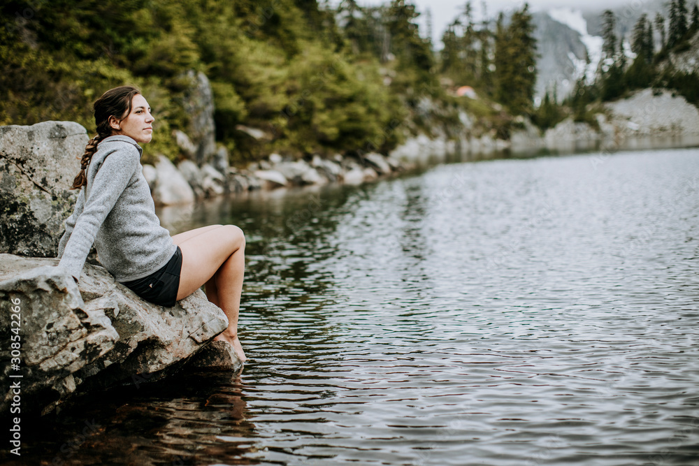 a female hiker dips her toes in Snow Lake, Snoqualmie Pass, Washington a female hiker dips her toes in Snow Lake, Snoqualmie Pass, Washington