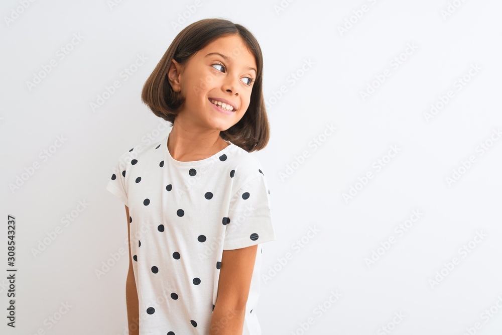 Young beautiful child girl wearing casual t-shirt standing over isolated white background looking away to side with smile on face, natural expression. Laughing confident. Young beautiful child girl wearing casual t-shirt standing over isolated white background looking away to side with smile on face, natural expression. Laughing confident.