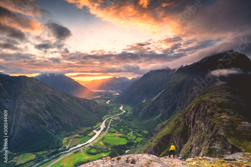 Elevated view of man standing on Romsdalseggen ridge admiring Rauma valley during sunset, Andalsnes, More og Romsdal photo