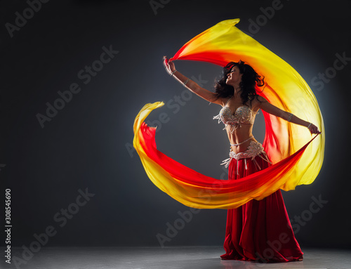 Foto beautiful black-haired girl in red ethnic dress on the stage dances oriental dan