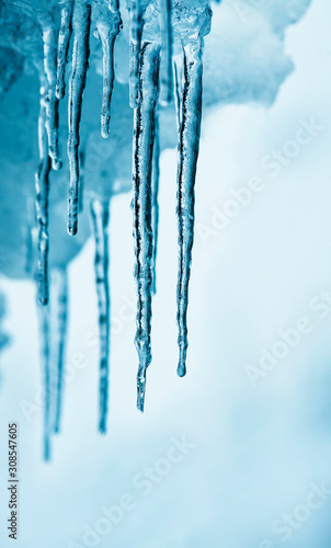 beautiful natural background with shiny transparent blue icicles hanging down in winter day © nataba