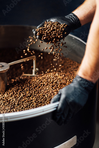 worker took Freshly roasted coffee to check the quality of mixer drum for cooling