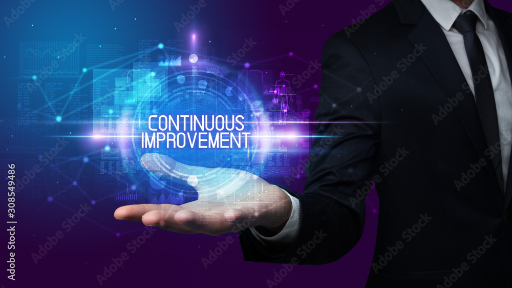 Man hand holding CONTINUOUS IMPROVEMENT inscription, technology concept Man hand holding CONTINUOUS IMPROVEMENT inscription, technology concept