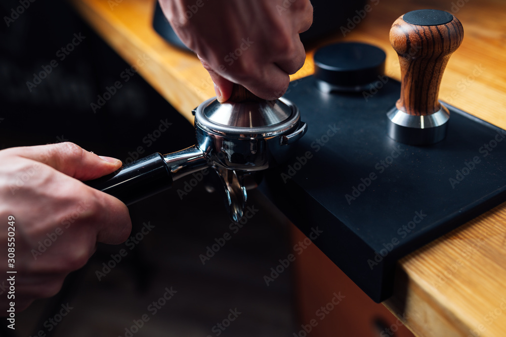 tempering coffee in portafilter on a dark background