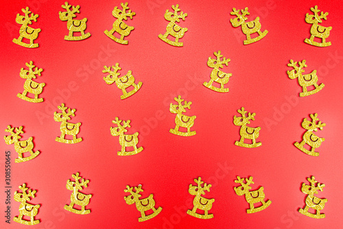 Background made of gold reindeer arranged randomly on a red background.
