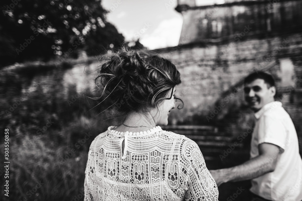 A wonderful love story. Young couple walking around the old wall of castle. Black and white A wonderful love story. Young couple walking around the old wall of castle. Black and white
