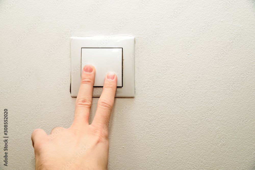 The hand presses the light switch. The concept of saving electricity, turning on the light in dark days. The hand presses the light switch. The concept of saving electricity, turning on the light in dark days.