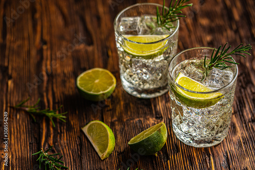 Gin and tonic with lime and ice on wooden table