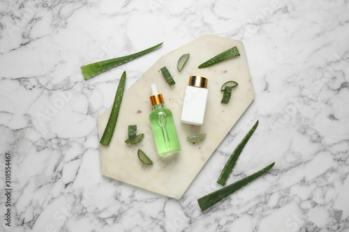 Flat lay composition with aloe vera and cosmetic products on white marble background