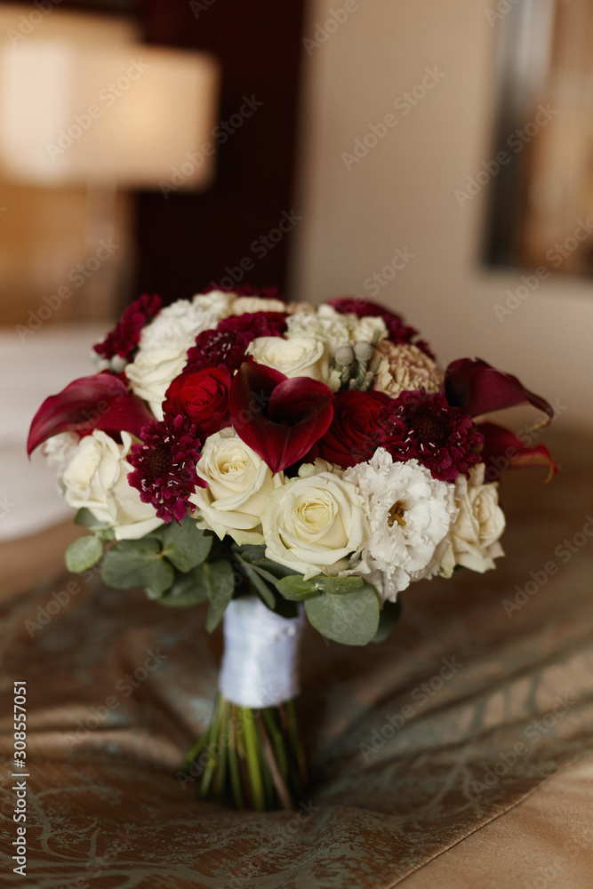 Obraz premium Lush bridal bouquet of exotic flowers, closeup, blurred background. Concept wedding postcard. Luxury bridal bouquet with calla lilies and peony roses. Delicate wedding bouquet in white and red colors