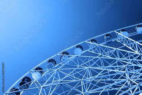 Ferris wheel against a blue cloudy sky toned in classic blue. Color of the year 2020. Colorful concept. 