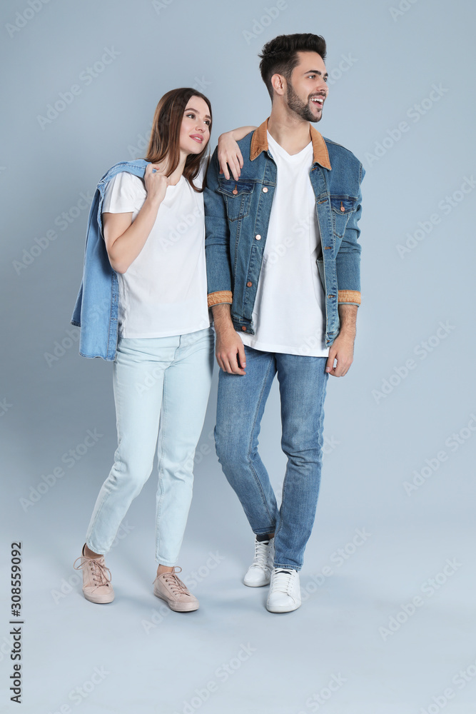 Young couple in stylish jeans on grey background Young couple in stylish jeans on grey background