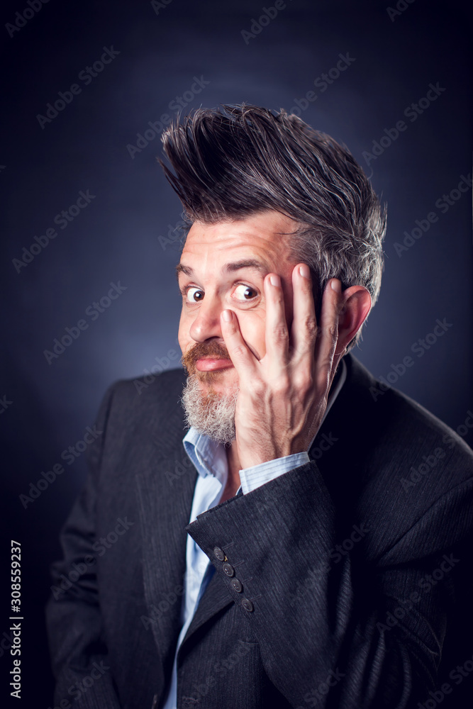 A portrait of bearded man with iroquois wearing suit covering his face with hand. People and emotions concept A portrait of bearded man with iroquois wearing suit covering his face with hand. People and emotions concept