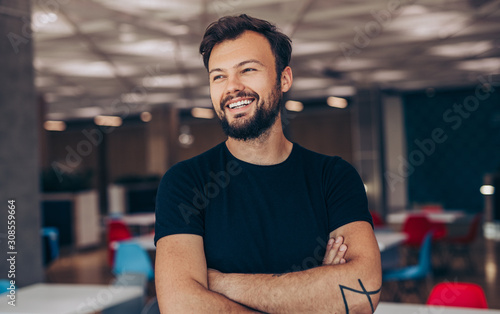 Cheerful guy with crossed arms in cafe