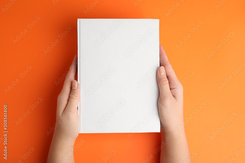 Woman holding book with blank cover on orange background, top view ...