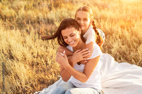 Daughter hugging mother on rural sunny field