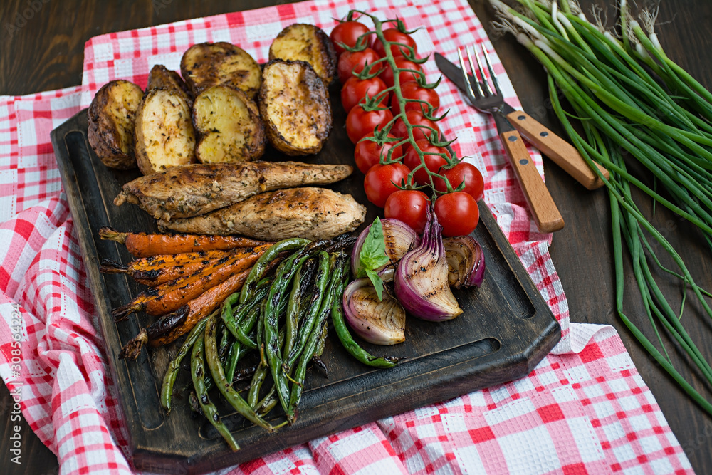 Grilled vegetables on a cutting board on a dark wooden background. Dark wooden background. Grilled vegetables on a cutting board on a dark wooden background. Dark wooden background.