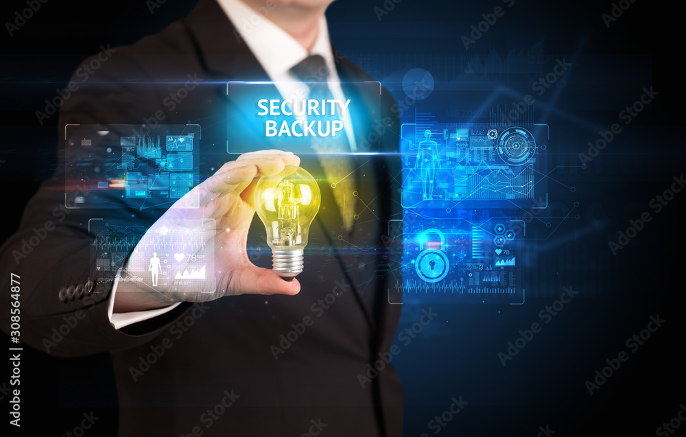 Fototapeta premium Businessman holding lightbulb with SECURITY BACKUP inscription, online security idea concept