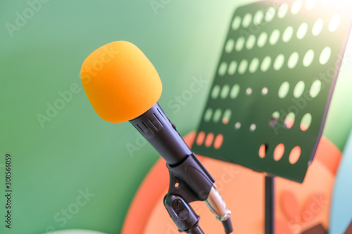 Close-up of orange head microphone in the classroom singing for children Green-white wall backdrop with book stand.