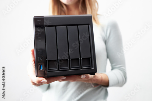 girl person hold in hands portable office or home data nas server. device for backup important information. copy space. four hdd slots and usb version 3 plug. photo