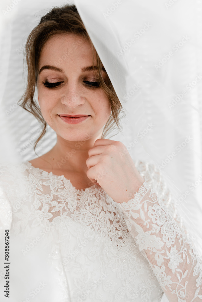 Portrait of young gorgeous bride with bridal veil. Wedding day gatherings. Beautiful girl dresses and gathers for a wedding ceremony in apartaments while waiting for the groom. Bride's morning Portrait of young gorgeous bride with bridal veil. Wedding day gatherings. Beautiful girl dresses and gathers for a wedding ceremony in apartaments while waiting for the groom. Bride's morning