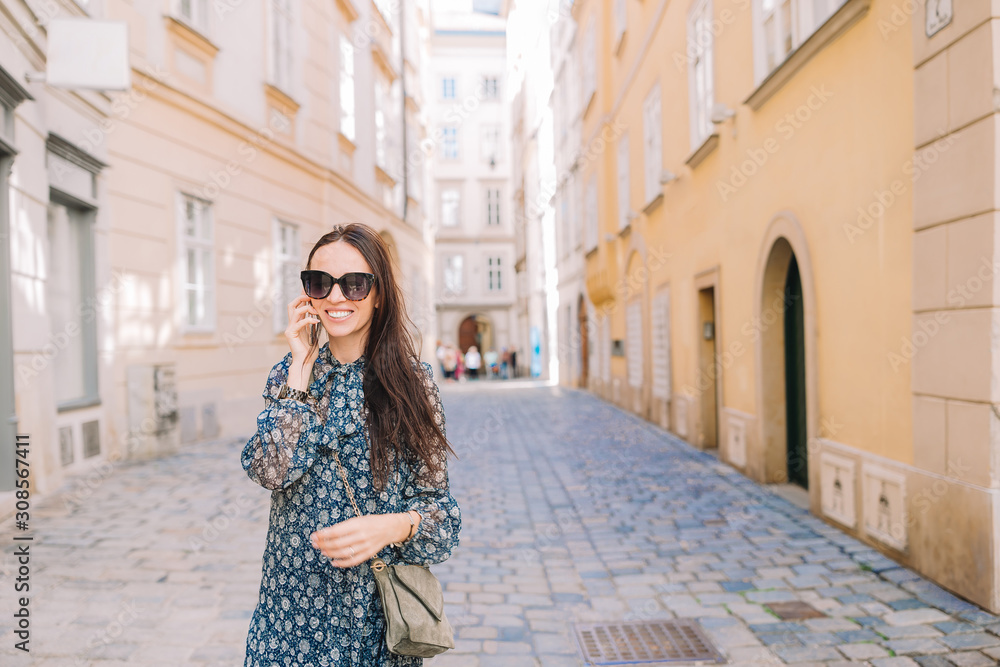 Fototapeta premium Woman talk by her smartphone in city. Young attractive tourist outdoors in italian city