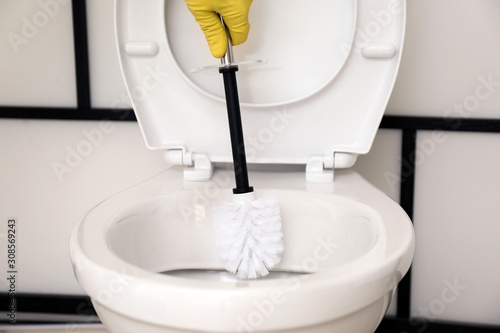 Fototapeta Naklejka Na Ścianę i Meble -  Man cleaning toilet bowl in bathroom, closeup