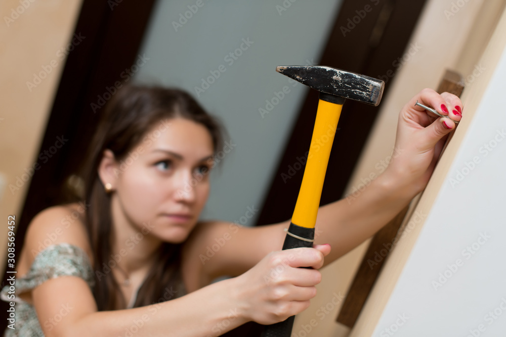 Girl is going to hammer a nail into the wall for photo frame Stock Photo |  Adobe Stock