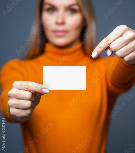 Amazing young woman holding a mockup blank business card and points with a finger on the card photo