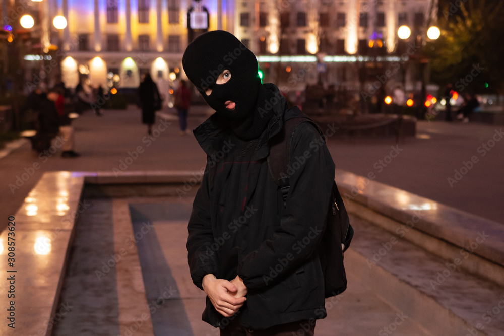 man in a balaclava in the middle of the night city. man in a balaclava in the middle of the night city.