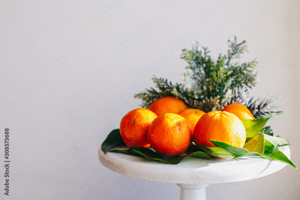 Orange tangerines on grey background in New Year's decor with brown pine cones and green leaves. Christmas decoration with mandarins. Delicious sweet clementine. Orange tangerines on grey background in New Year's decor with brown pine cones and green leaves. Christmas decoration with mandarins. Delicious sweet clementine.