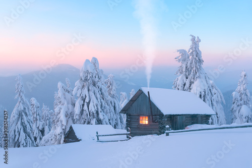Fototapeta Fantastic winter landscape with wooden house in snowy mountains