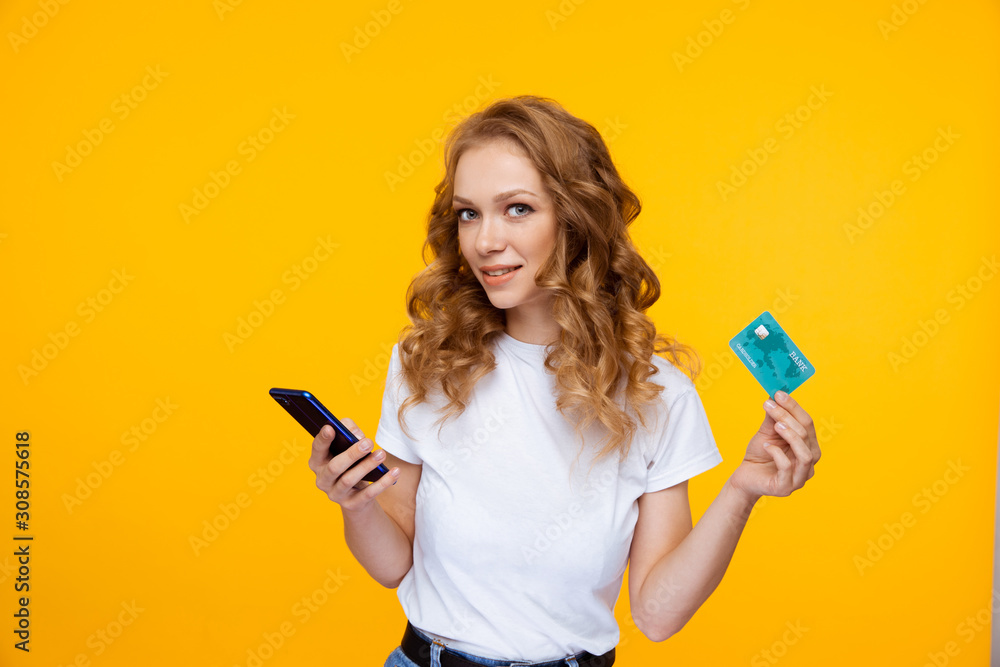 Pretty woman holding credit card and phone isolated - obrazy, fototapety, plakaty 