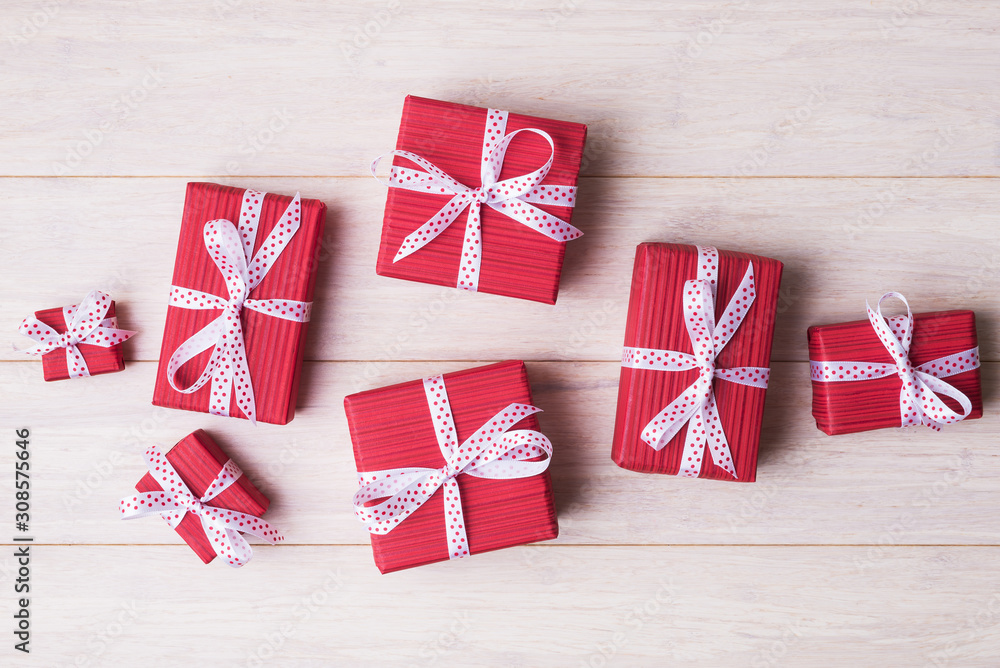 Obraz premium Red gift boxes with spotted bows over light wooden background with copy space