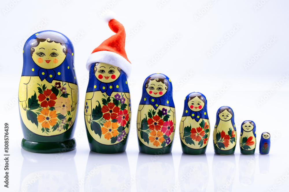 Reihe von Matroschka isoliert auf weißem Hintergrund mit Spiegelung, wobei eine Puppe eine Weihnachtsmütze trägt