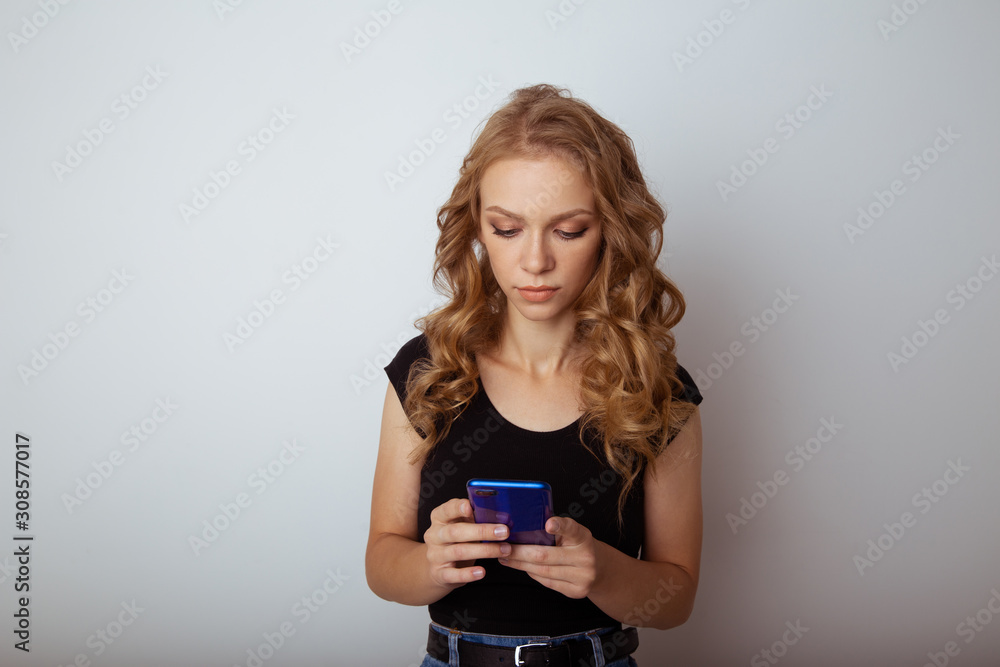 Pretty female in black t-shurt holding blue phone isolated in the white studio Pretty female in black t-shurt holding blue phone isolated in the white studio