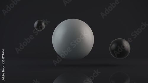 3D rendering of a large glowing white sphere and two black balls placed side by side. The objects are in a dark Studio. Abstract composition of ideal figures, a combination of white and black.