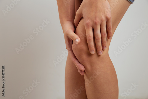 Sore knee concept. Young woman holding her leg with pain