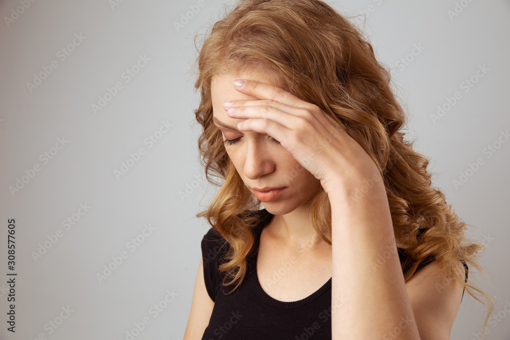 Pain in head concept. Blond woman feeling bad and holding her hands on head
