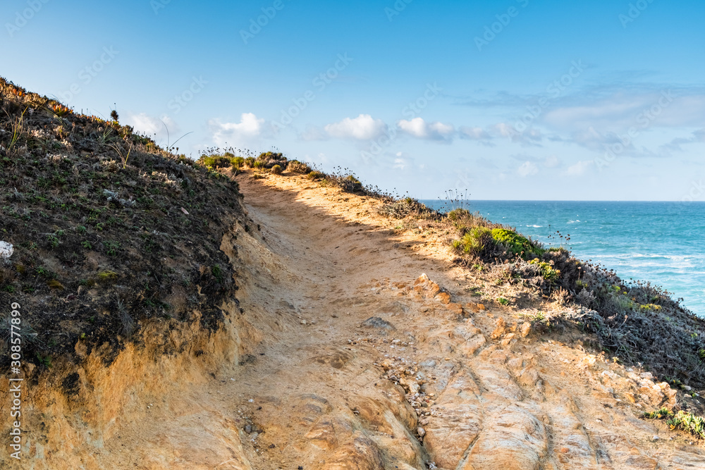 Atlantic ocean coast - Rota Vicentina trekking sign, wild beaches and cliffs in Aljezur, Portugal