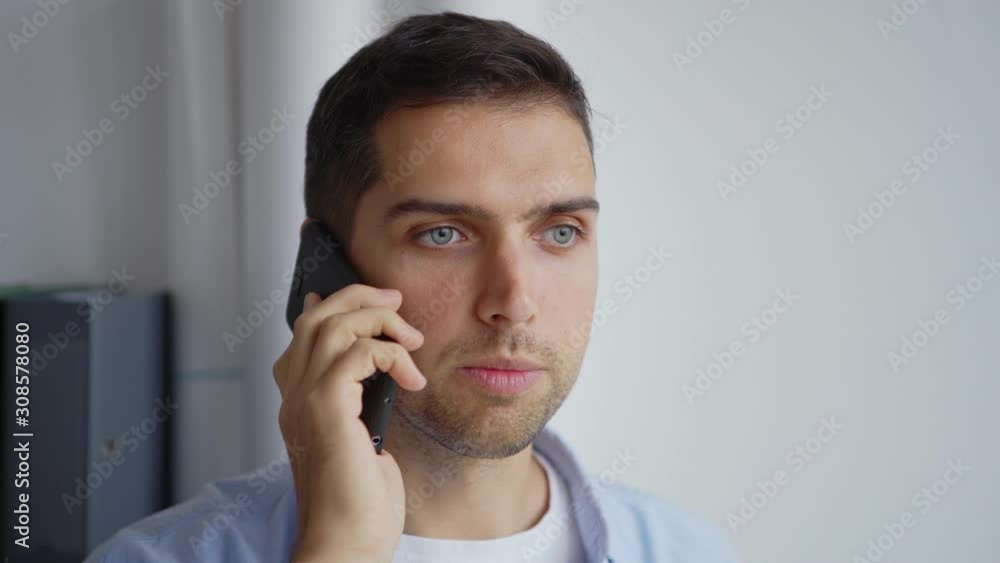 Tilt up closeup shot of young businessman holding open laptop computer and talking on cell phone standing in office Tilt up closeup shot of young businessman holding open laptop computer and talking on cell phone standing in office