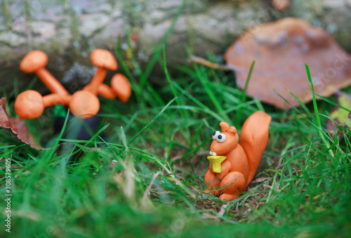 Wallpaper Mural Plasticine world - small homemade squirrel holds in paws chanterelle and sitting on a green meadow surrounded plasticine mushrooms, selective focus Torontodigital.ca