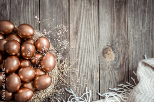 Background with Golden Easter eggs on wooden background.