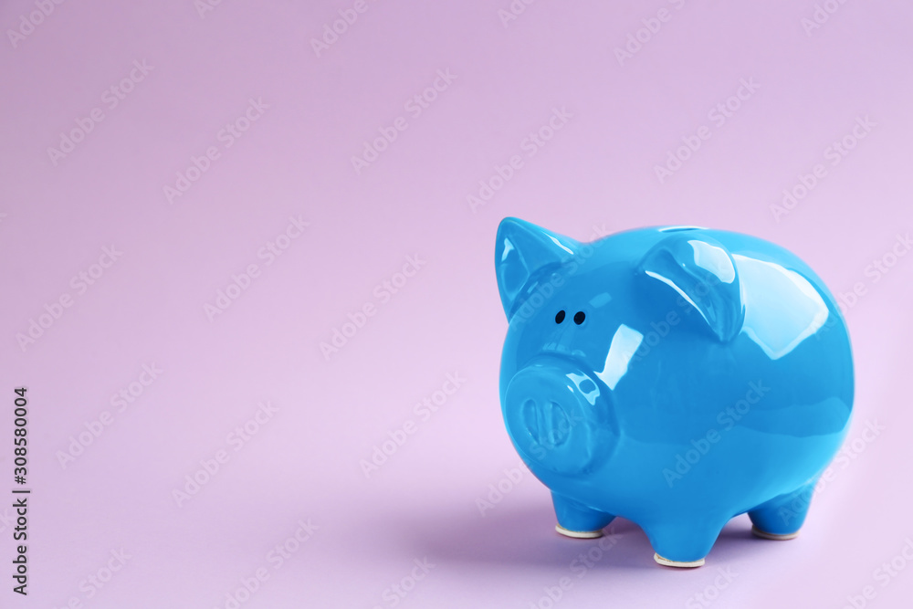 Blue piggy bank on violet background. Space for text