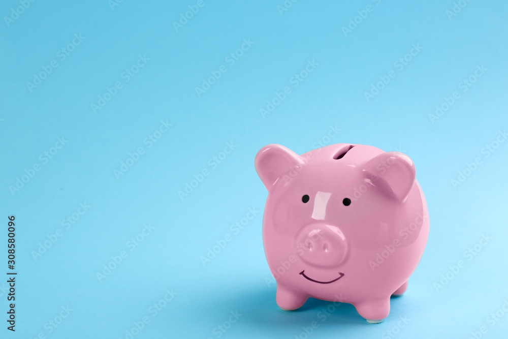 Pink piggy bank on light blue background. Space for text