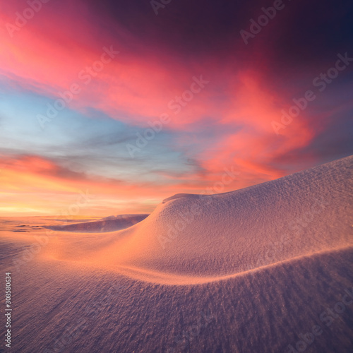 Fototapeta Naklejka Na Ścianę i Meble -  Fantastic winter landscape in snowy mountains glowing by evening sunlight. Dramatic wintry scene with frozen snowy hills at sunset. Christmas holiday background